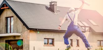 Arbeiter springend auf Wiese vor Haus